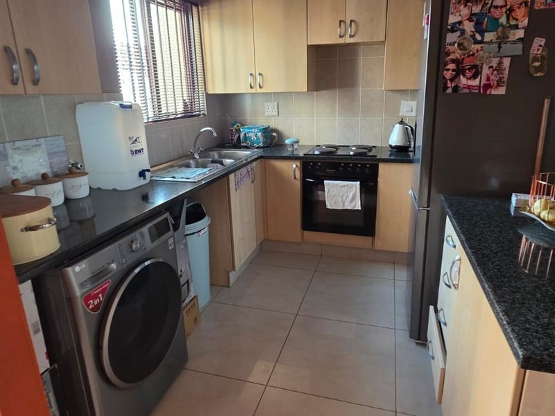 A functional kitchen featuring light wood cabinetry, granite countertops, a tiled backsplash, and a convenient breakfast island, providing ample storage and workspace.
