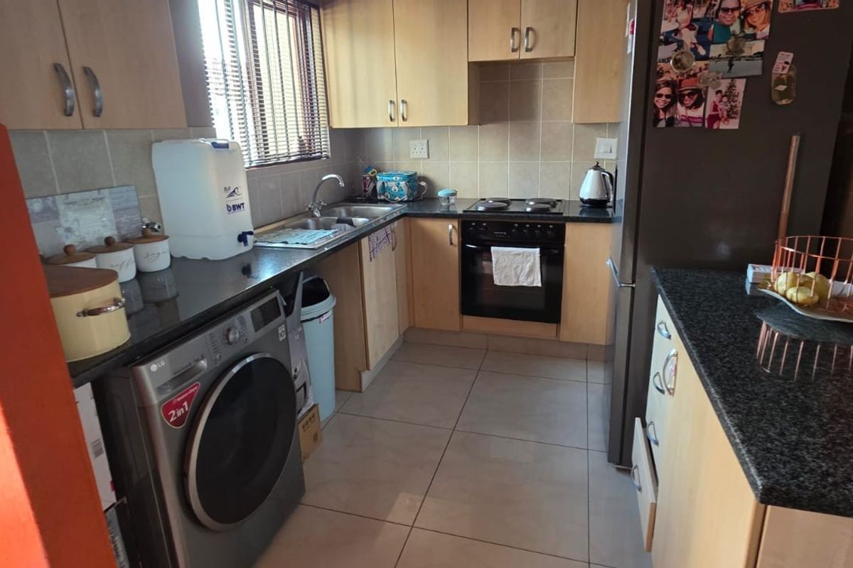 A functional kitchen featuring light wood cabinetry, granite countertops, a tiled backsplash, and a convenient breakfast island, providing ample storage and workspace.