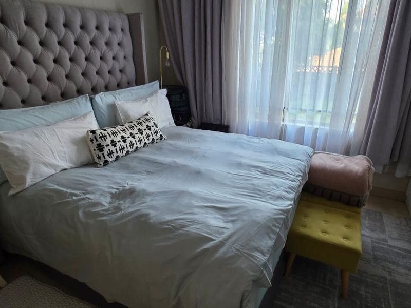 A well-maintained bedroom featuring a large built-in wardrobe and floor-to-ceiling curtains, providing a comfortable and functional living space.