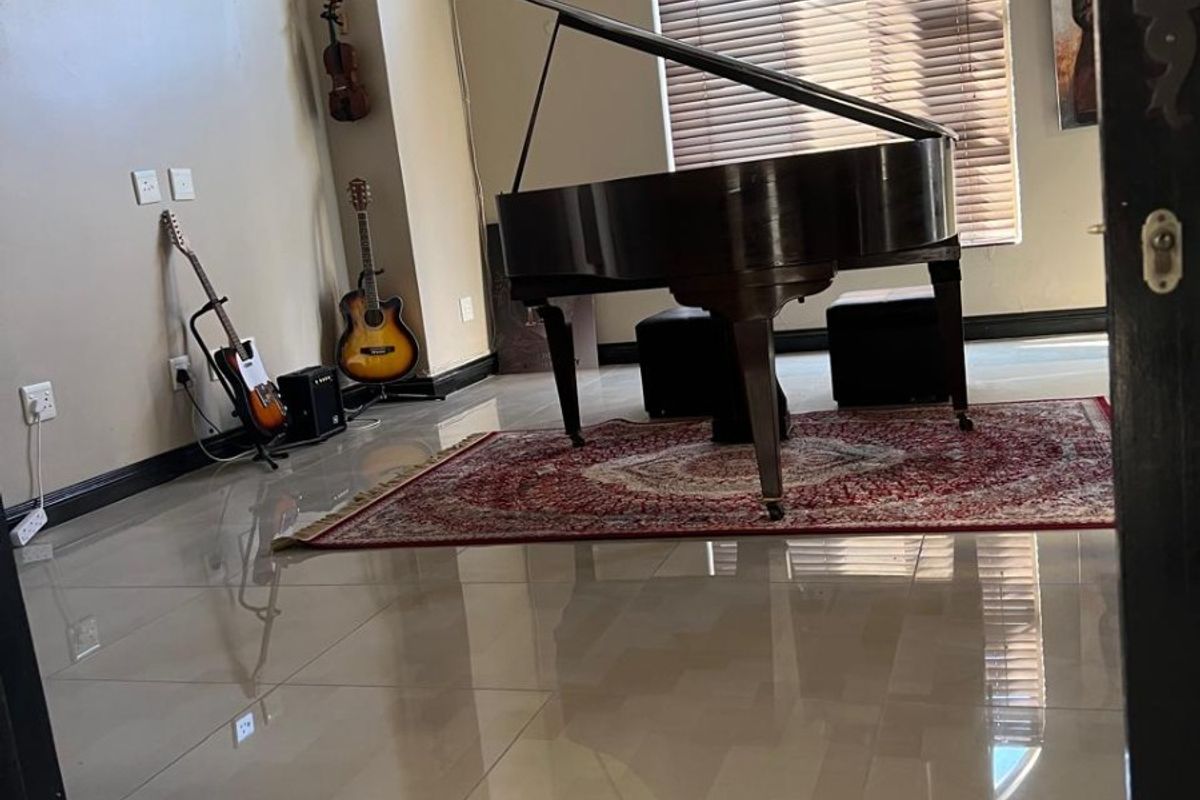 Spacious living area featuring polished tiled flooring, recessed lighting, and a large arched window with fitted blinds.