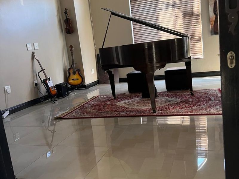 Spacious living area featuring polished tiled flooring, recessed lighting, and a large arched window with fitted blinds.