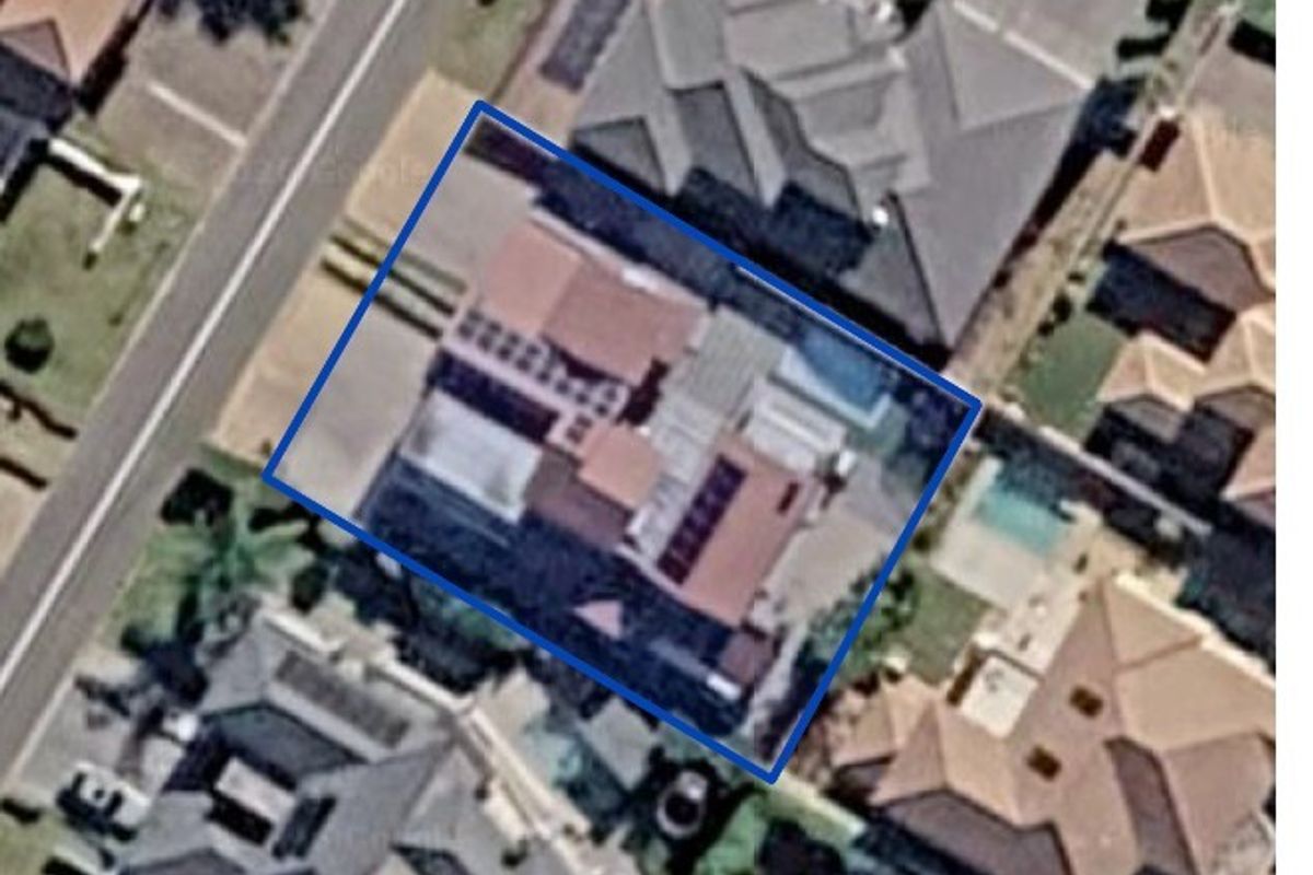 An aerial view of the property highlighting the roof structure, solar panel installation, and the swimming pool area within the residential lot.