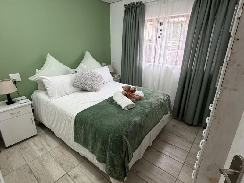 A cozy bedroom featuring tiled flooring and a painted tongue and groove ceiling, offering a comfortable and functional living space.