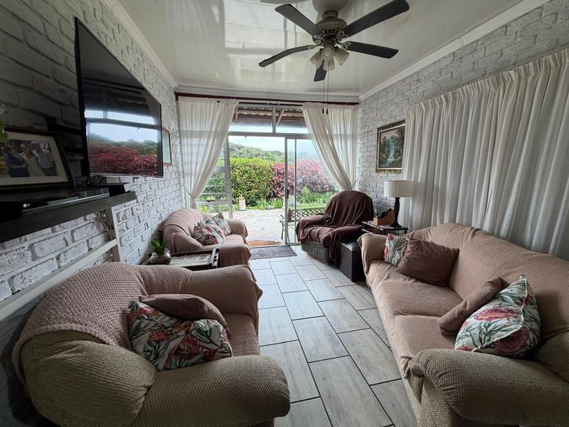A cozy living room featuring exposed brick walls, tiled flooring, and a ceiling fan, with direct access to an outdoor patio area.