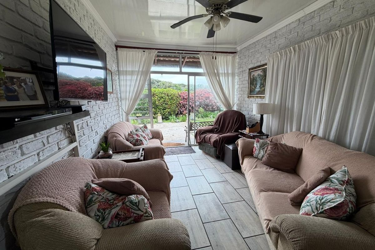 A cozy living room featuring exposed brick walls, tiled flooring, and a ceiling fan, with direct access to an outdoor patio area.