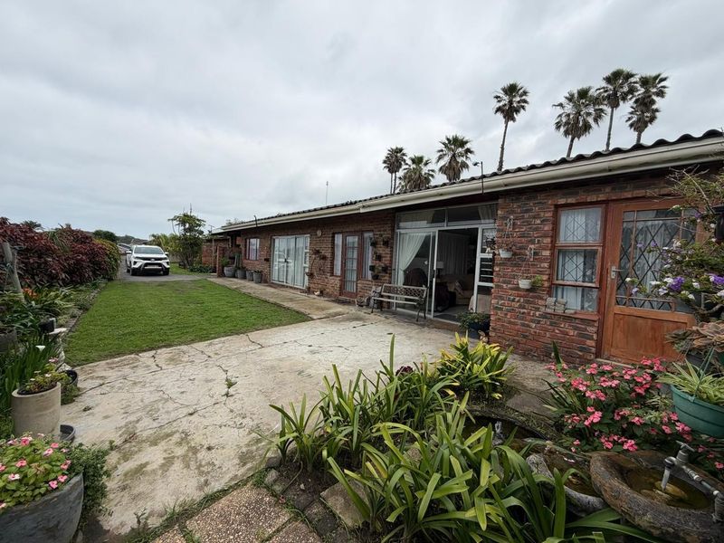 Rear view of a face brick house featuring a concrete patio, sliding glass doors, and a well-maintained garden area.