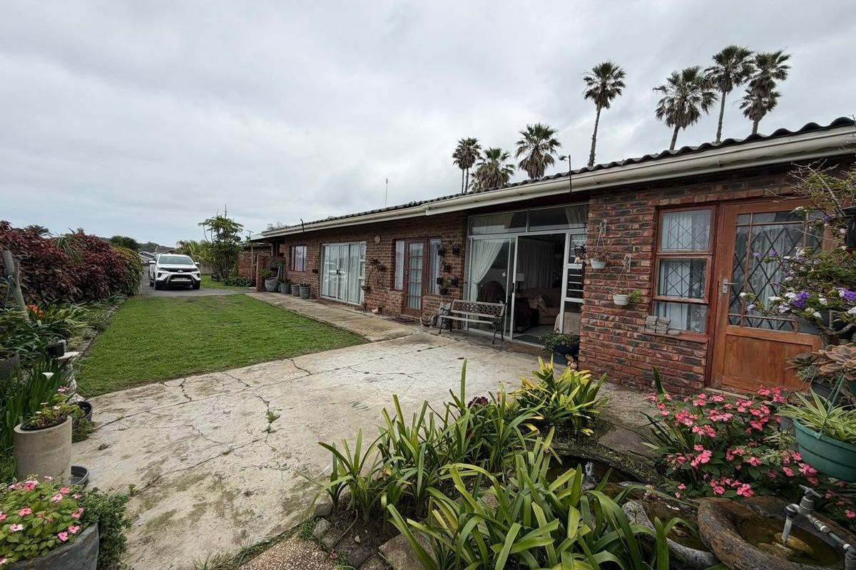 Rear view of a face brick house featuring a concrete patio, sliding glass doors, and a well-maintained garden area.