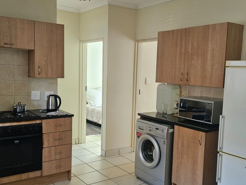 Functional kitchen featuring wood-look cabinetry, built-in oven, electric hob, and tiled flooring, providing a practical layout for daily meal preparation.