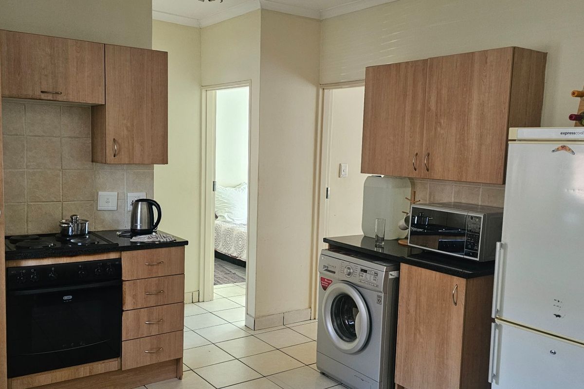 Functional kitchen featuring wood-look cabinetry, built-in oven, electric hob, and tiled flooring, providing a practical layout for daily meal preparation.