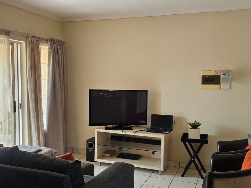 A comfortable living room featuring tiled flooring and a sliding glass door that provides access to the outdoor area.