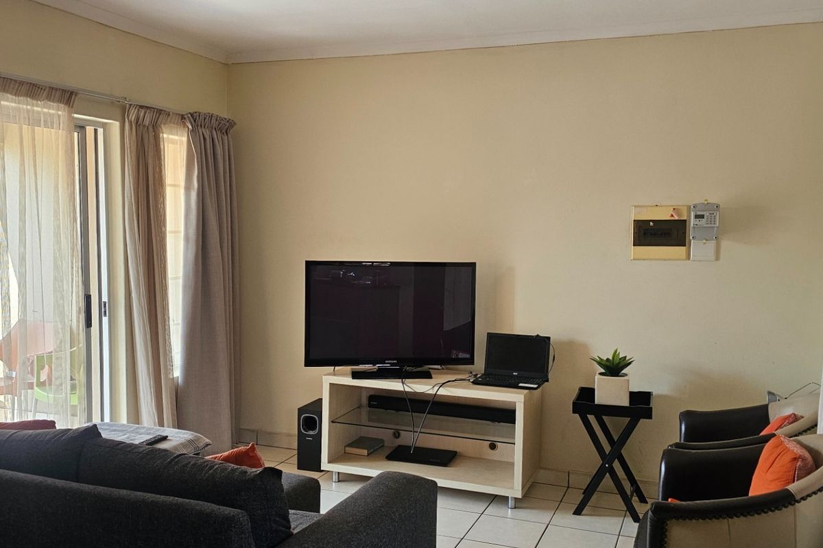 A comfortable living room featuring tiled flooring and a sliding glass door that provides access to the outdoor area.