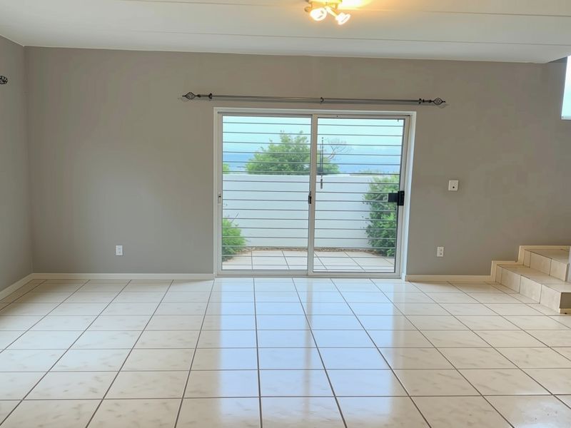 Spacious, light-filled living area featuring neutral tiled flooring, a sliding door with security gate, and an internal staircase.