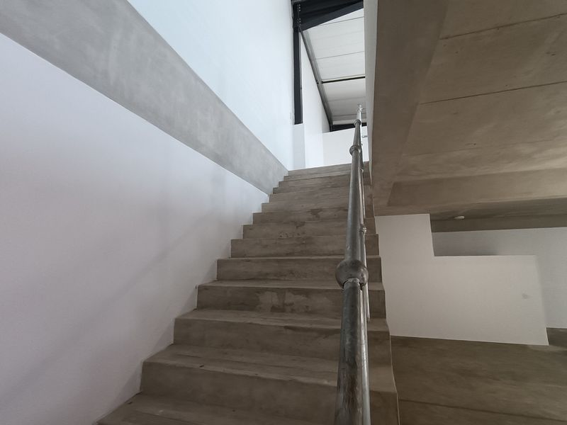 Modern industrial-style interior featuring a concrete staircase with a metal handrail and exposed structural steel elements.