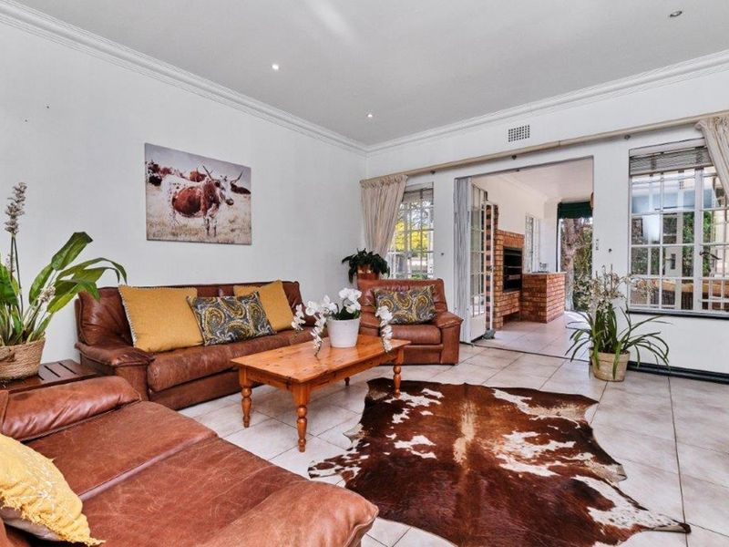 Spacious living room featuring tiled flooring, recessed lighting, and large sliding glass doors that open onto a covered patio with a built-in fireplace.