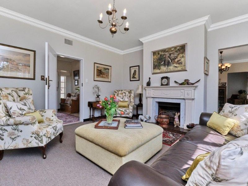 A cozy living room featuring a traditional fireplace with a decorative mantelpiece, crown molding, and coved ceiling details.