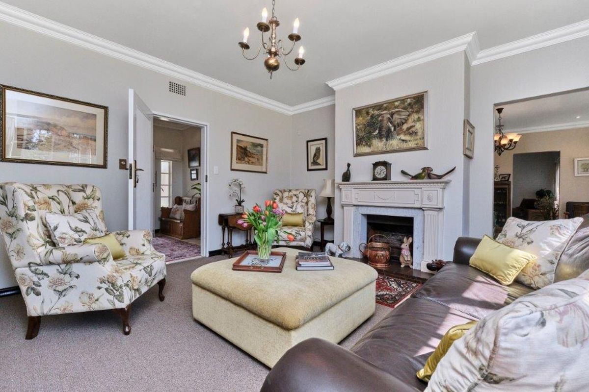 A cozy living room featuring a traditional fireplace with a decorative mantelpiece, crown molding, and coved ceiling details.