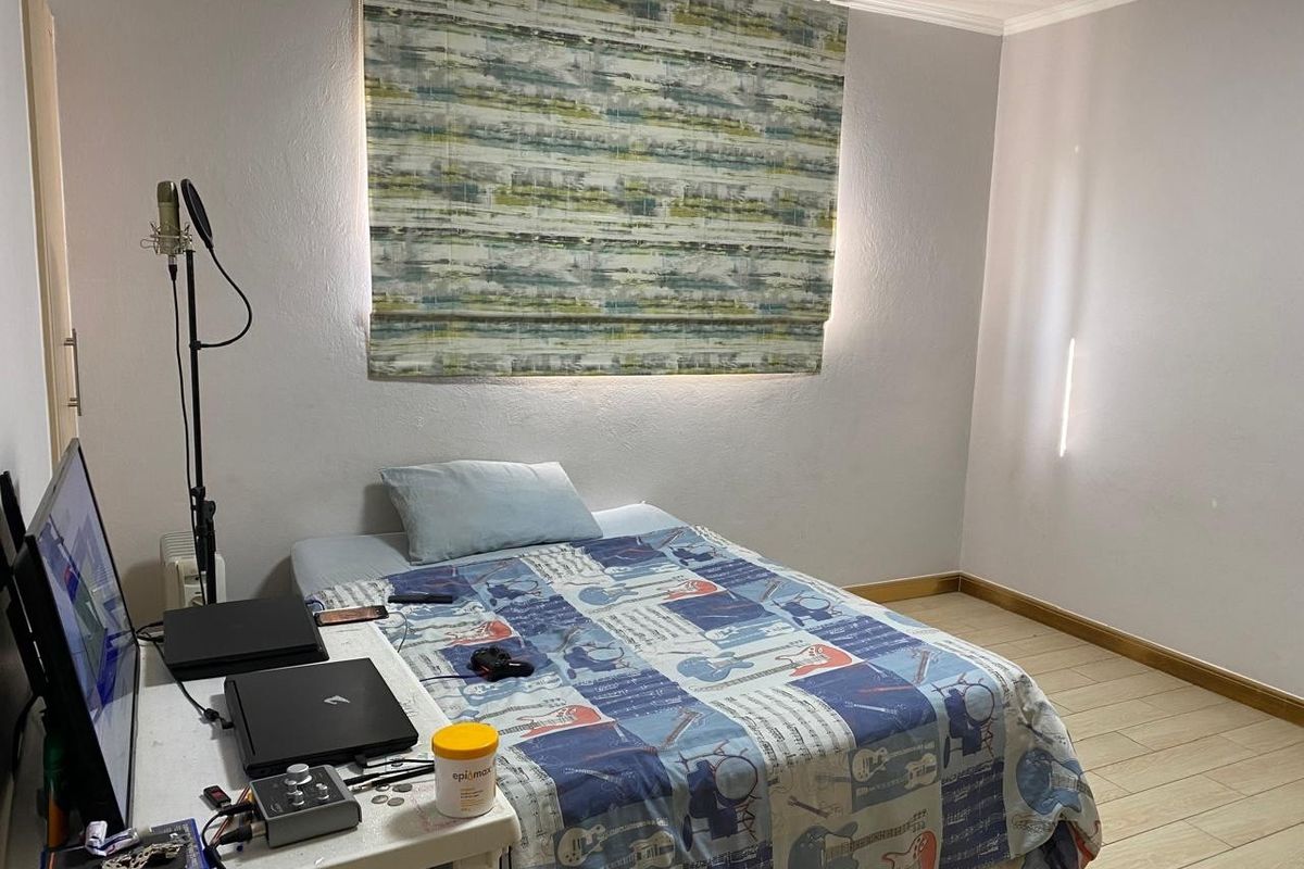 A functional bedroom featuring tiled flooring and a patterned roman blind, providing a neutral base for personalization.