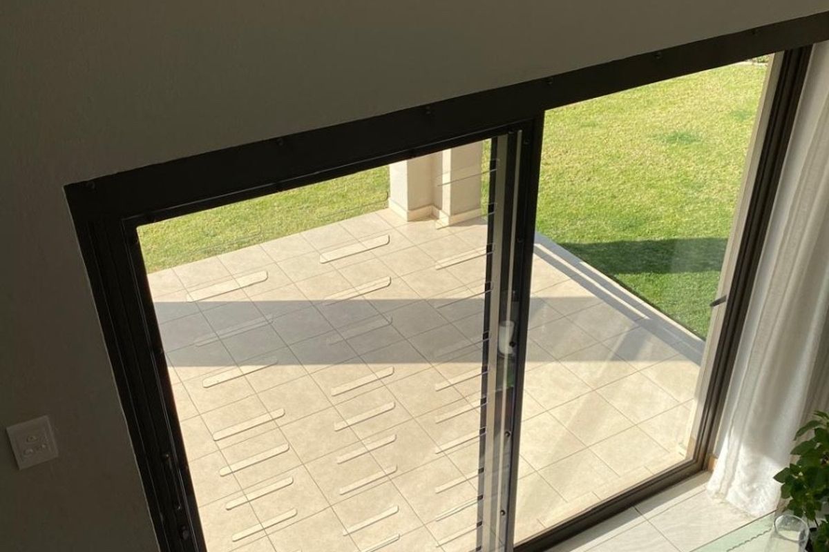 A view from the staircase looking down into a living area with large sliding glass doors opening onto a paved patio and garden.