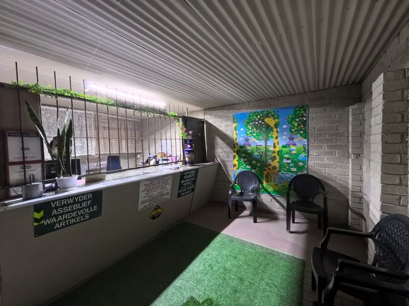A commercial reception or service entry area featuring a service counter, security bars, and exposed brick walls with a corrugated metal ceiling.