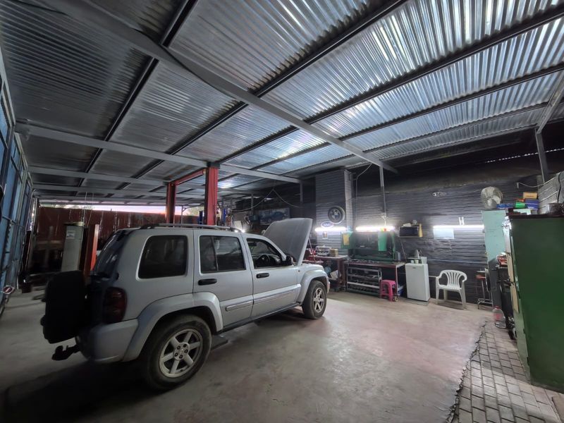 A functional commercial garage space featuring a high corrugated metal roof, exposed steel structural beams, and durable concrete flooring.