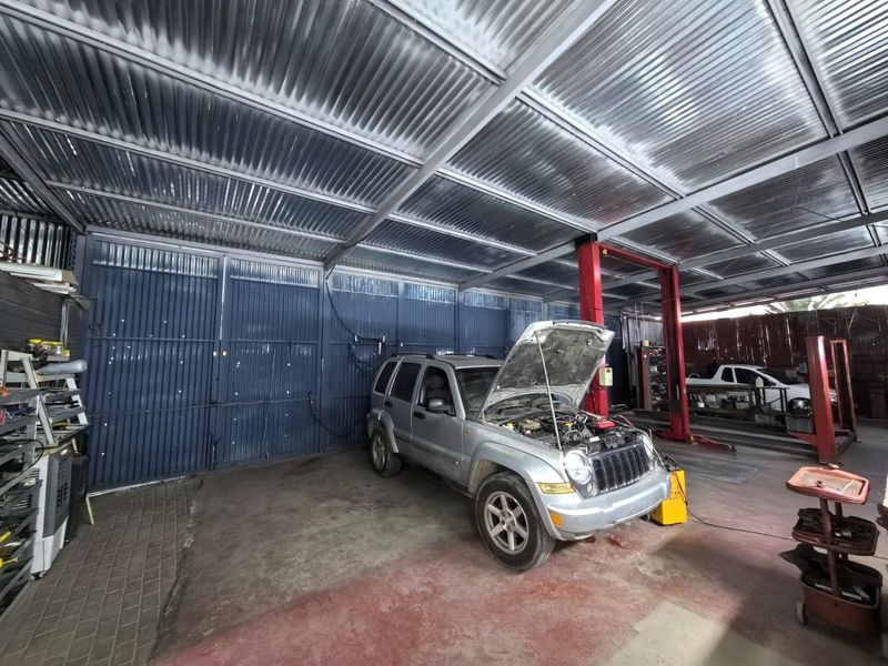 A functional commercial garage space featuring a high corrugated metal roof, steel support beams, and an integrated vehicle lift system.