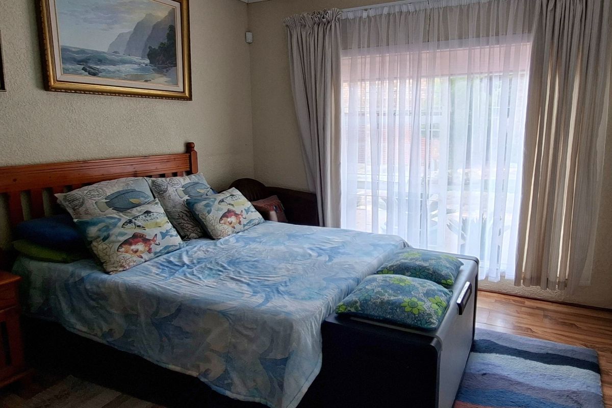 A bedroom featuring wooden flooring, a ceiling fan, and a sliding glass door providing access to the exterior.