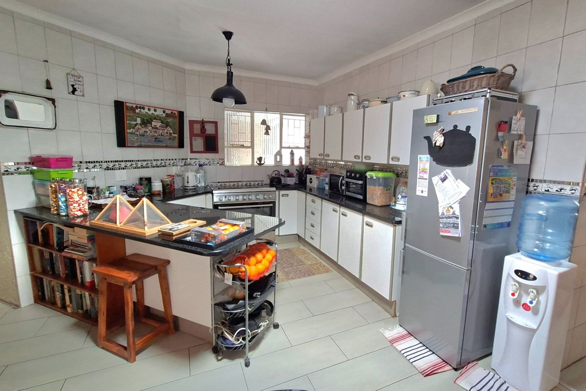 A functional kitchen featuring granite countertops, ample built-in cabinetry, a gas stove, and tiled finishes throughout, offering a practical layout for daily cooking.