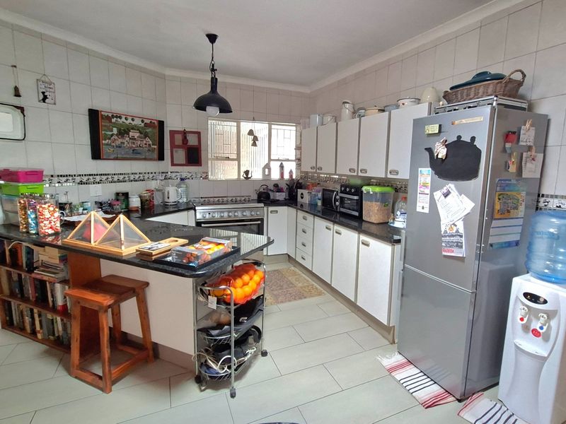 A functional kitchen featuring granite countertops, ample built-in cabinetry, a gas stove, and tiled finishes throughout, offering a practical layout for daily cooking.