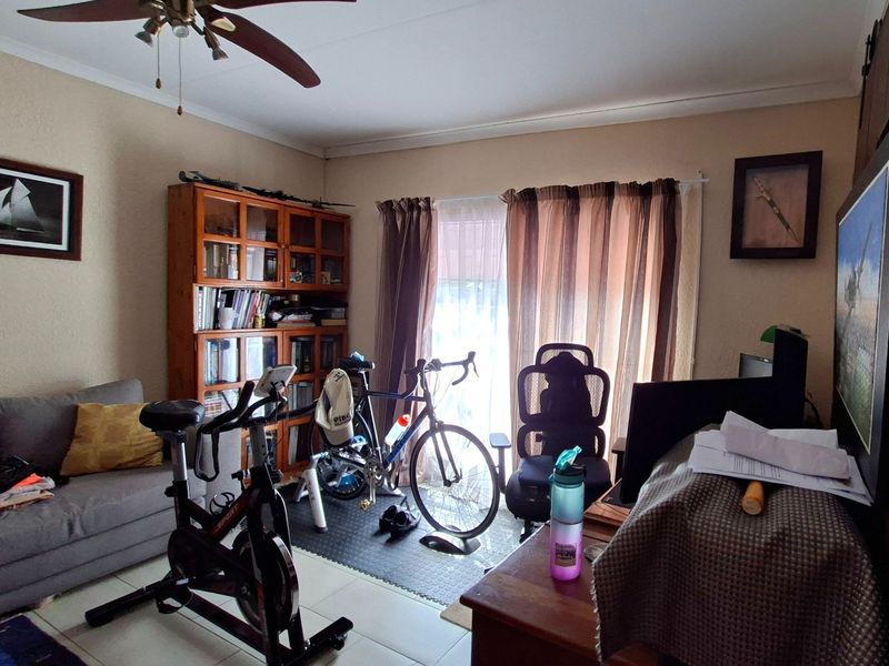 A functional office space featuring tiled flooring, a ceiling fan, and a sliding glass door providing natural light.