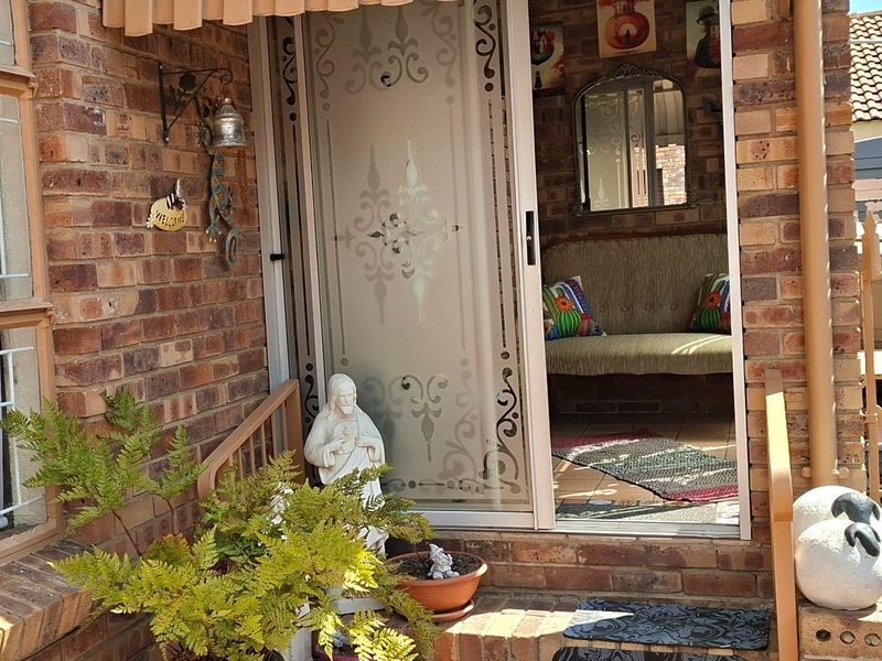 Front entrance featuring a brick facade, sliding glass door with decorative etching, and a fabric awning over the paved step area.