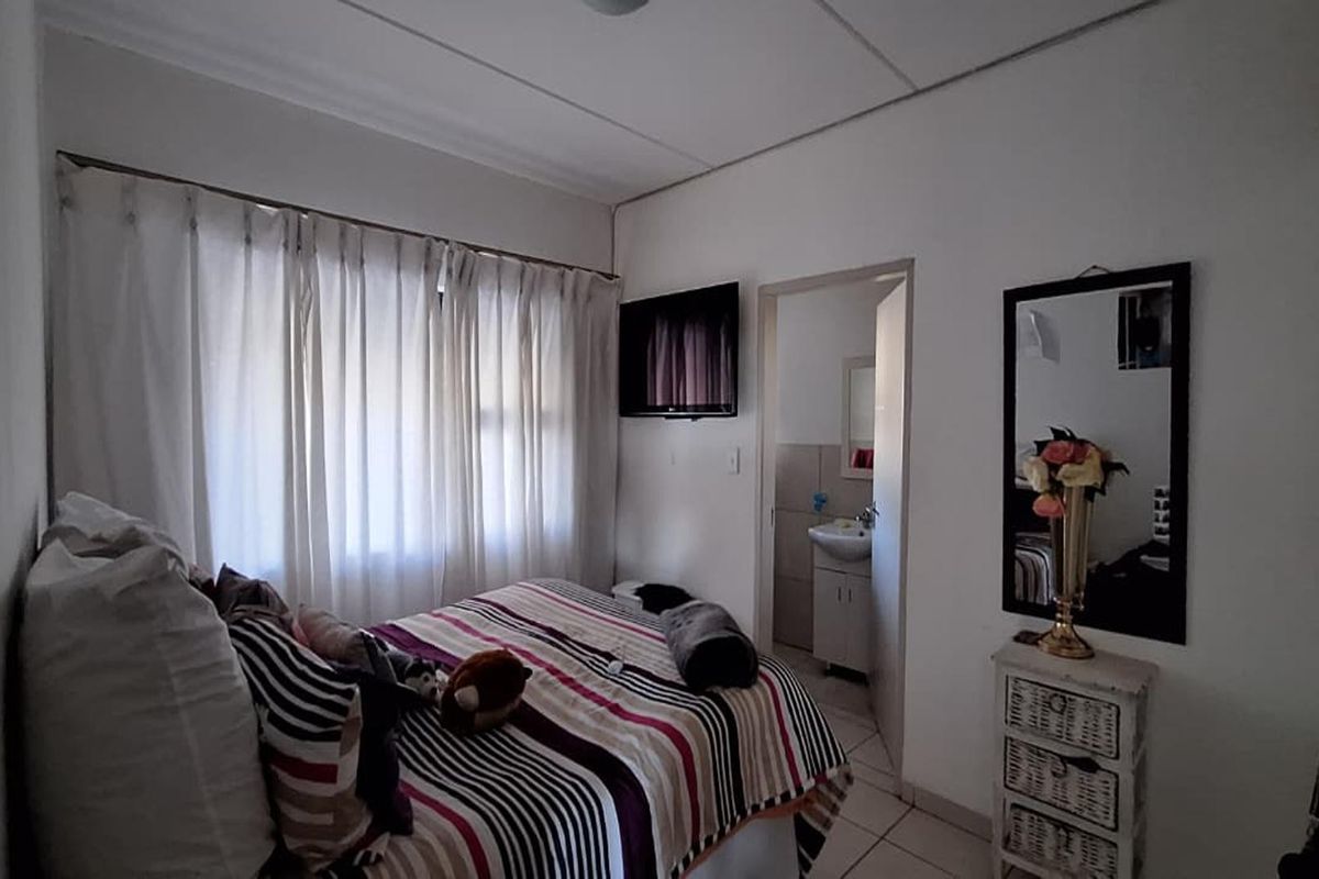 A functional bedroom featuring tiled flooring and direct access to an en-suite bathroom, offering a practical layout for comfortable living.