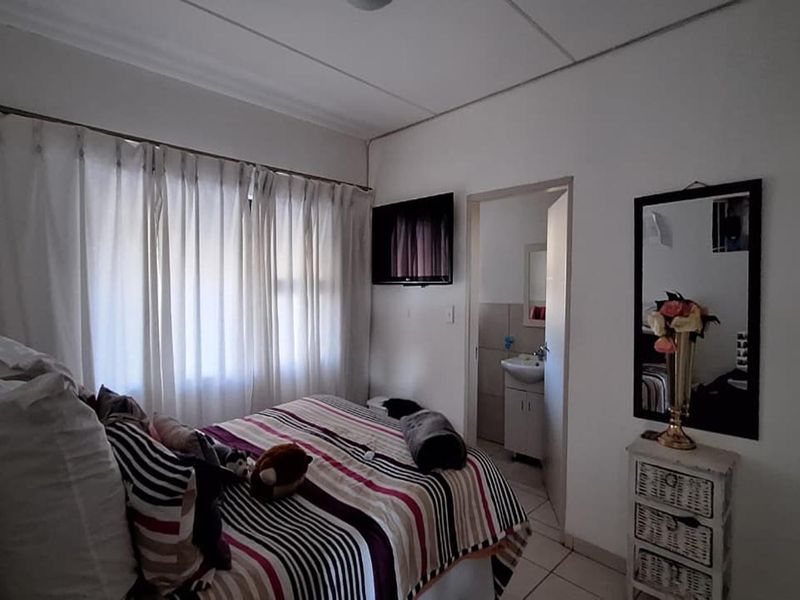 A functional bedroom featuring tiled flooring and direct access to an en-suite bathroom, offering a practical layout for comfortable living.