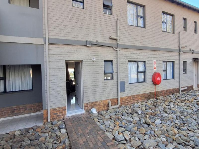 Front elevation of a multi-story townhouse complex featuring painted brickwork, casement windows, and a paved entrance path.