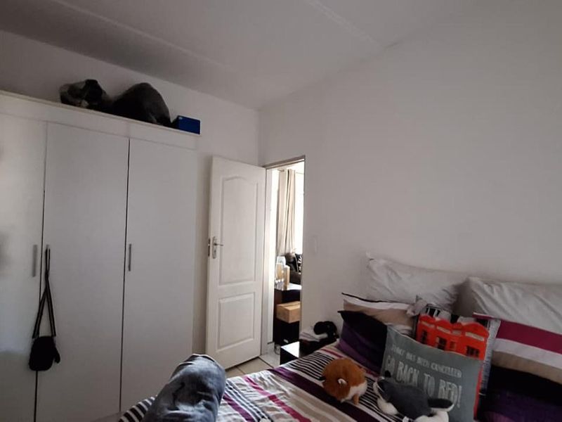 A bedroom featuring a built-in wardrobe with overhead storage space and a doorway leading to an adjacent room.