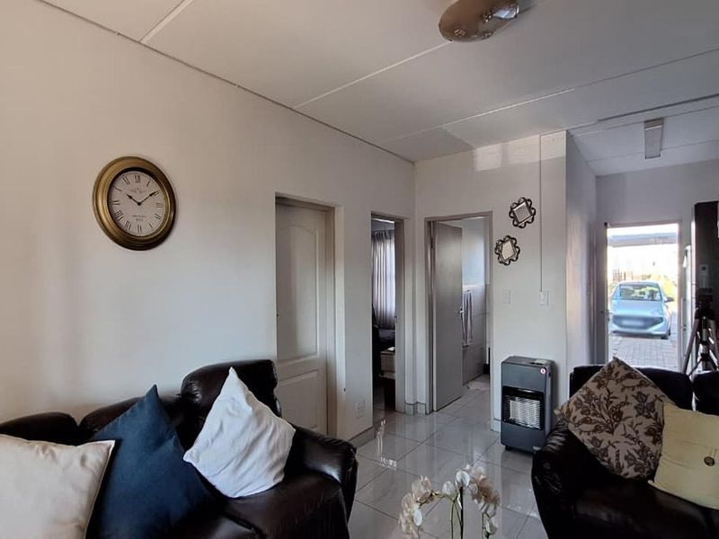Open plan living area featuring tiled flooring and direct access to the kitchen and hallway, providing a functional layout for the townhouse.