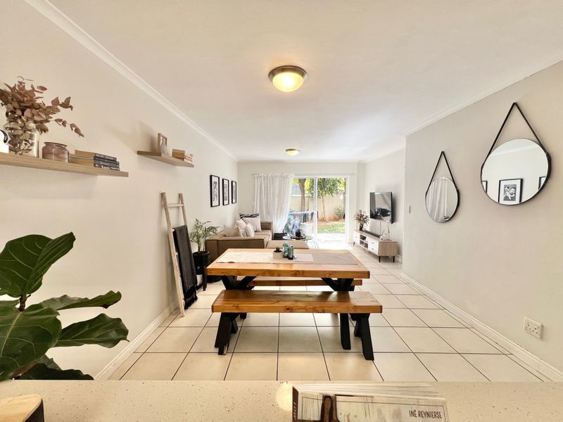 An open-plan living and dining area featuring neutral walls, tiled flooring, and a sliding glass door providing access to the rear garden.