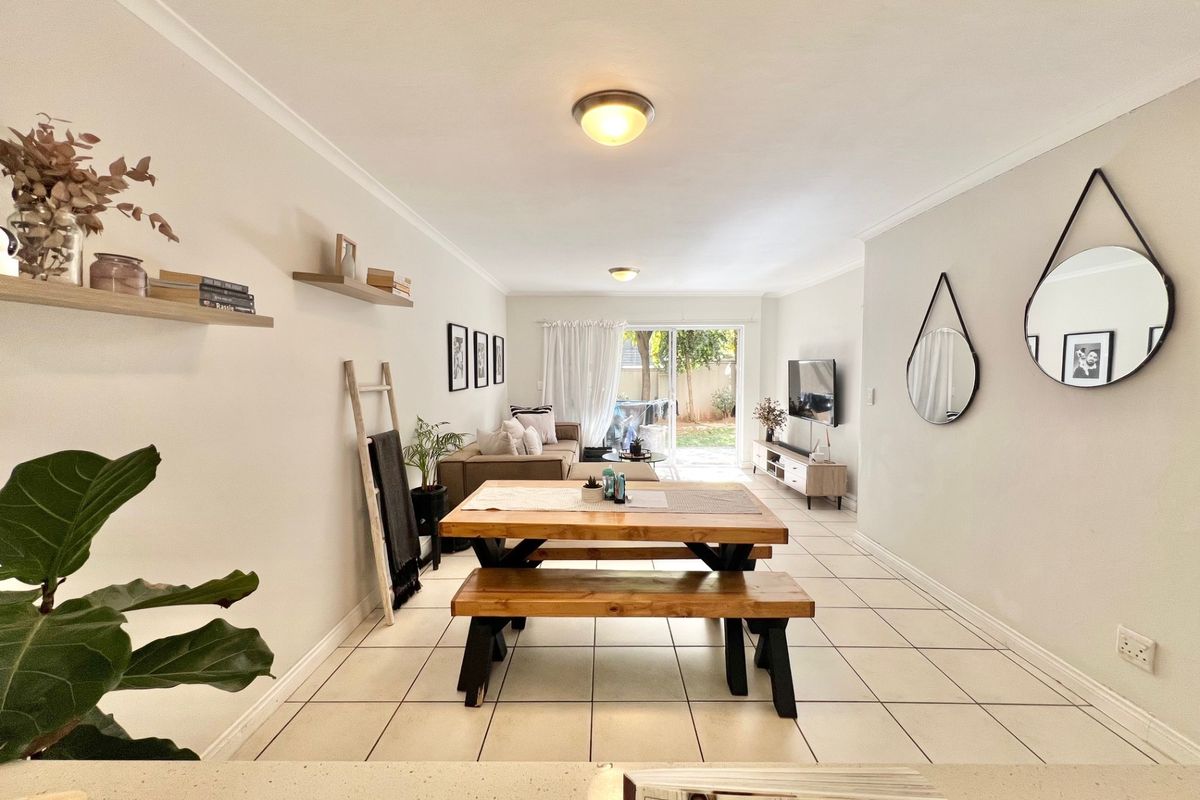 An open-plan living and dining area featuring neutral walls, tiled flooring, and a sliding glass door providing access to the rear garden.