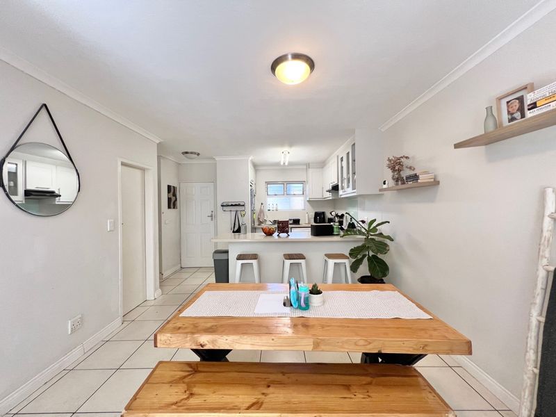 An open-plan living and kitchen area featuring tiled flooring, a breakfast bar, and neutral cabinetry, creating a functional and connected living space.