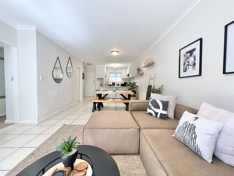An open-plan living and dining area featuring neutral tiled flooring, coved ceilings, and a seamless transition into the functional kitchen space.
