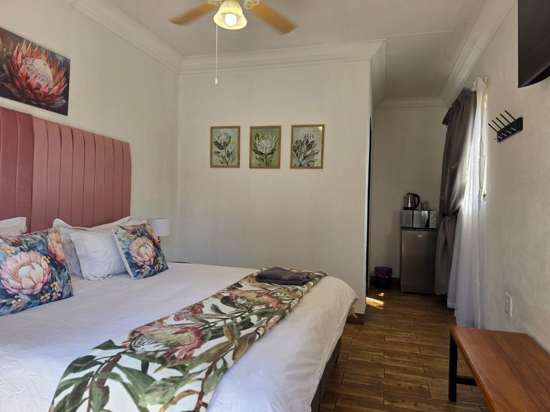 A well-maintained bedroom featuring tiled flooring, a ceiling fan, and crown molding, providing a comfortable and functional space for guests.