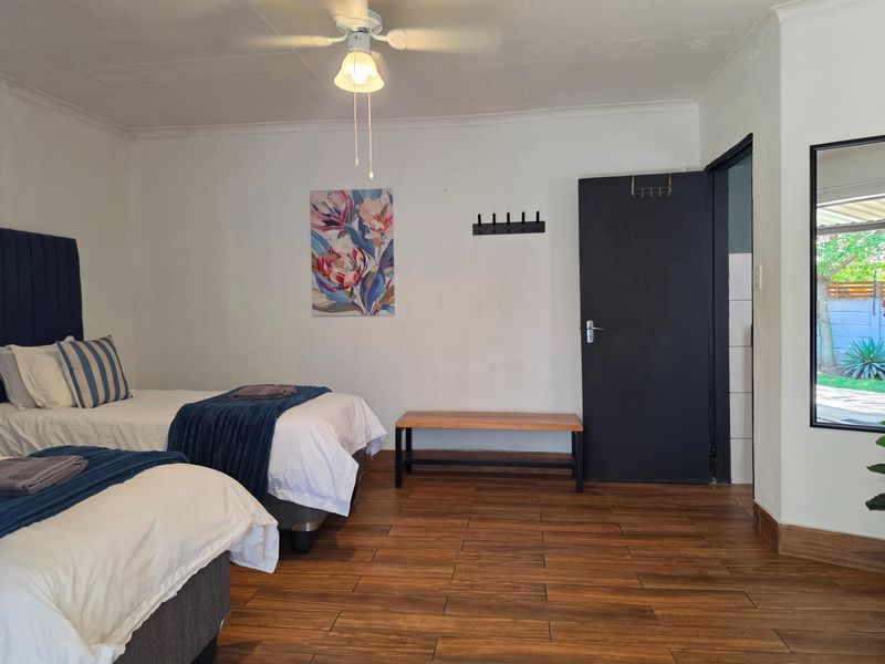 A well-maintained bedroom featuring wood-look tile flooring, a ceiling fan, and direct access to an outdoor area.