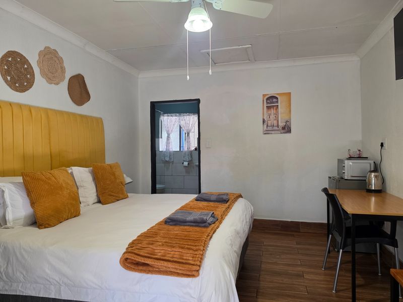 A bedroom featuring tiled flooring, a ceiling fan, and direct access to an en-suite bathroom.