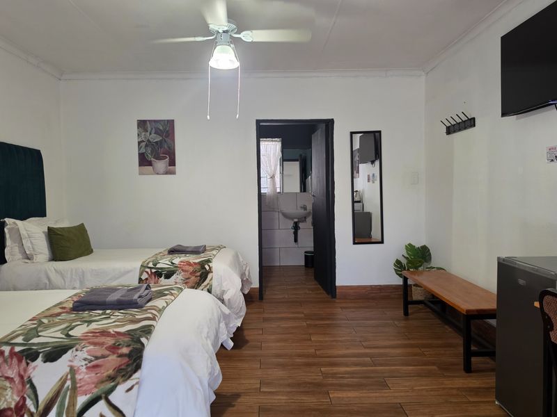 A well-maintained bedroom featuring tiled flooring, a ceiling fan, and direct access to an en-suite bathroom.