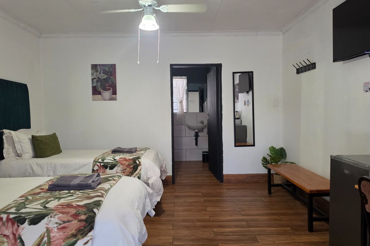 A well-maintained bedroom featuring tiled flooring, a ceiling fan, and direct access to an en-suite bathroom.