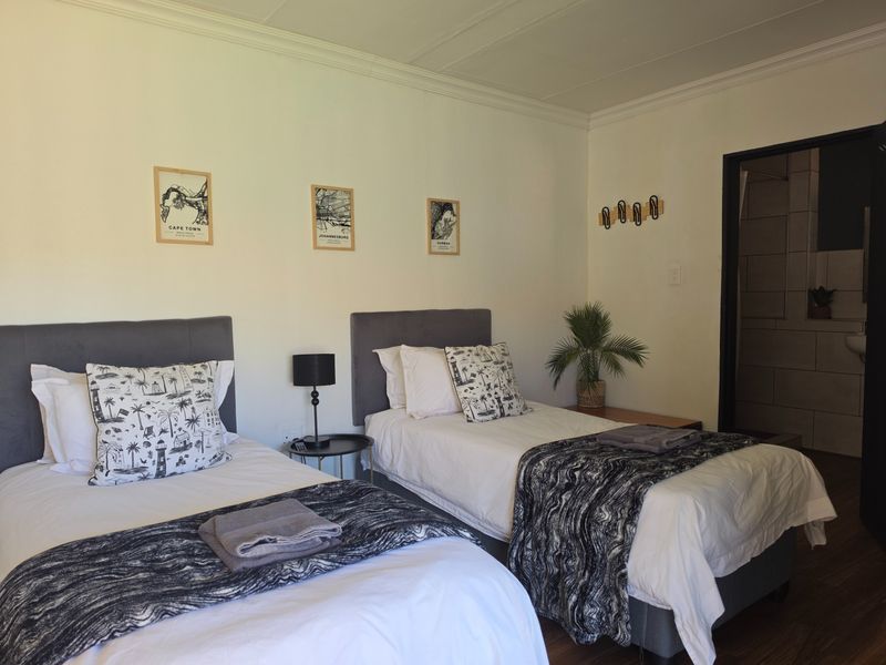 A well-maintained bedroom featuring laminate flooring, crown molding, and an en-suite bathroom entrance, offering a clean and functional guest accommodation space.
