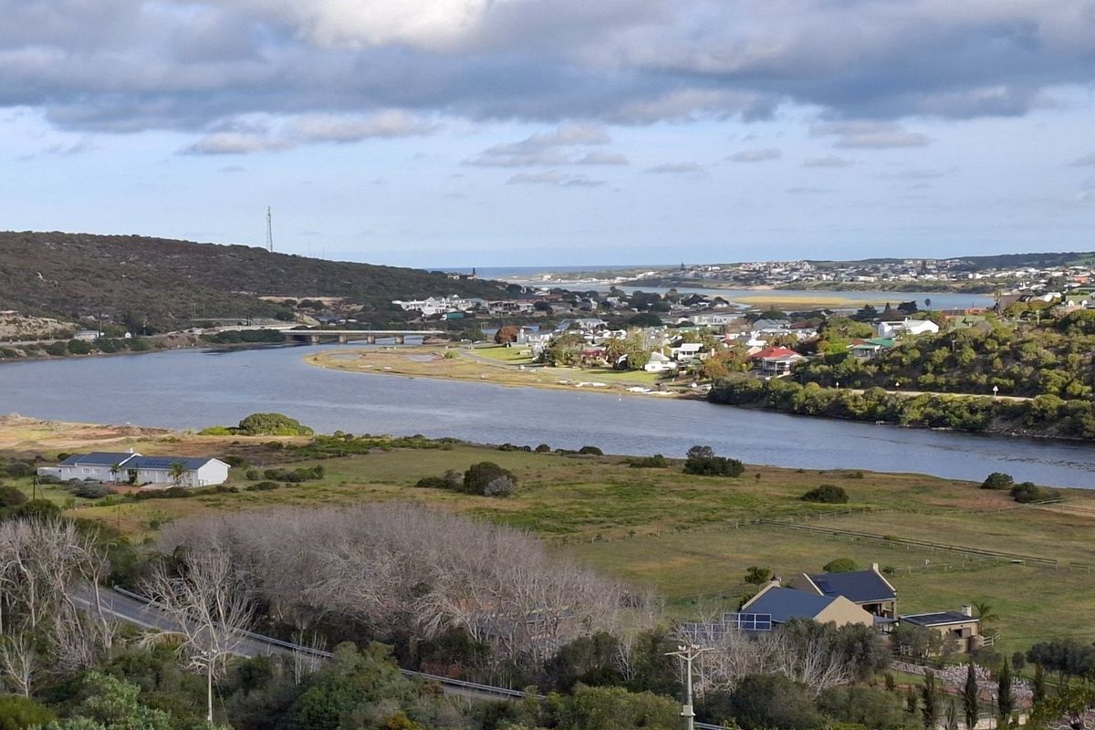 A scenic elevated view overlooking a river, surrounding landscape, and distant residential coastal town.