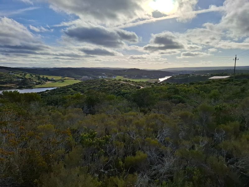 A scenic elevated view of the surrounding natural landscape, featuring rolling hills, native vegetation, and a river in the distance.