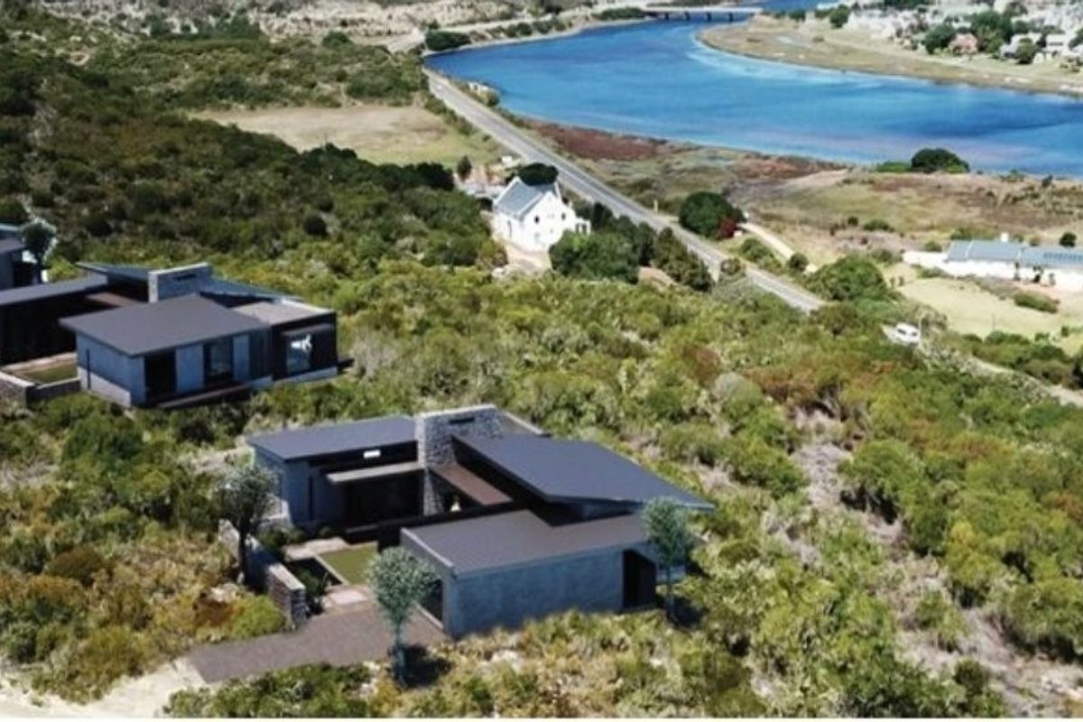 Aerial view of modern residential properties situated in a coastal landscape with views of the nearby river and surrounding natural vegetation.