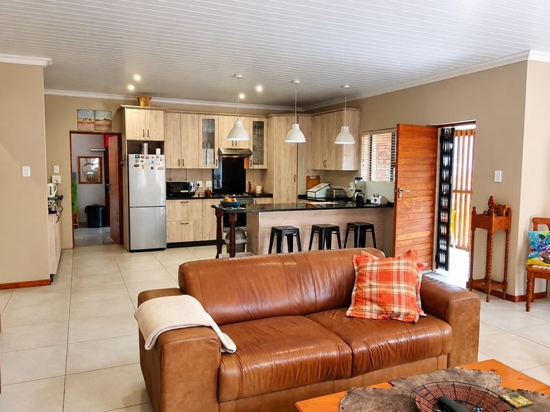 Spacious open-plan living area featuring a modern kitchen with granite countertops, ample cabinetry, and tiled flooring, seamlessly flowing into the lounge space.