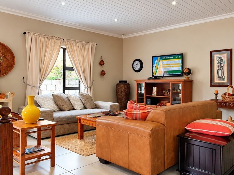 A comfortable living room featuring tiled flooring, recessed downlighting, and a classic tongue and groove ceiling, creating a warm and inviting atmosphere.